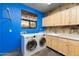 Functional laundry room with modern washer and dryer, light wood cabinets, and vibrant blue walls at 14426 N Vista Del Oro --, Fort McDowell, AZ 85264