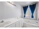 Bathroom with double vanity, tub, white cabinets, and blue curtains at 15002 W Heritage Oak Way, Surprise, AZ 85374