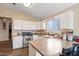 Well-lit kitchen with a breakfast bar, white cabinetry, and appliances at 15002 W Heritage Oak Way, Surprise, AZ 85374