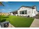Backyard featuring lush artificial grass, covered patio, and modern outdoor furniture, perfect for entertaining and relaxation at 17801 W Mountainair St, Surprise, AZ 85388