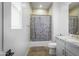 Bright bathroom featuring a shower with stylish curtain, vanity with marble countertop and light filled window at 17801 W Mountainair St, Surprise, AZ 85388