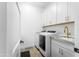 Bright laundry room features white cabinetry, gold hardware, and a modern washer and dryer at 17801 W Mountainair St, Surprise, AZ 85388
