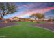 Expansive backyard featuring mature trees, lush lawn, landscape lighting, a covered patio, and outdoor living areas at 18919 W Verde Ln, Litchfield Park, AZ 85340
