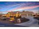 Stunning single-story home illuminated at twilight, showcasing its three-car garage, stone facade, and desert landscaping at 18919 W Verde Ln, Litchfield Park, AZ 85340
