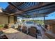 Outdoor kitchen with a dining area under a pergola, a built-in grill, fireplace, and a view of the sparkling pool at 18919 W Verde Ln, Litchfield Park, AZ 85340