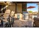 Well-equipped outdoor kitchen with stainless steel grill, refrigerator, sink, and bar seating under a covered patio at 18919 W Verde Ln, Litchfield Park, AZ 85340