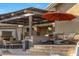 Inviting outdoor living space with a stone fireplace, outdoor kitchen, and comfortable lounge seating under a pergola at 18919 W Verde Ln, Litchfield Park, AZ 85340