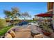Beautiful backyard swimming pool featuring a rock waterfall, mature shade trees and a covered outdoor kitchen at 18919 W Verde Ln, Litchfield Park, AZ 85340