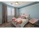 Bright bedroom with a ceiling fan, a white bed covered with toys, and curtains accenting the window at 1970 E Lafayette Ave, Gilbert, AZ 85298