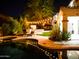 Night view of a backyard featuring a pool, spa, outdoor kitchen, and ambient string lights at 22339 N 77Th Way, Scottsdale, AZ 85255