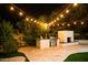 An inviting outdoor kitchen and fireplace with string lights enhance this entertainment area at 22339 N 77Th Way, Scottsdale, AZ 85255