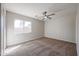 Bright bedroom featuring neutral carpet, a ceiling fan, neutral paint, and a large window at 22583 W Lasso Ln, Buckeye, AZ 85326