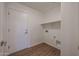 Bright laundry room with tile floor, convenient storage shelf, and a white door at 22583 W Lasso Ln, Buckeye, AZ 85326
