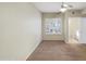 This bedroom has neutral walls, carpet flooring, a ceiling fan, and a window overlooking the backyard at 295 N Rural Rd # 128, Chandler, AZ 85226