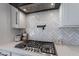 Close-up of a stovetop with herringbone tile backsplash and pot filler faucet, showcasing modern kitchen design elements at 4289 W Caribou Ln, Queen Creek, AZ 85142