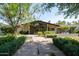 Modern home featuring a sleek glass facade, inviting entryway, and lush, manicured landscaping enhancing curb appeal at 6301 E Exeter Blvd, Scottsdale, AZ 85251