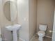 Cozy bathroom with pedestal sink, oval mirror, and toilet at 8613 S 49Th Dr, Laveen, AZ 85339