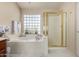 Bright bathroom with marble floors, soaking tub, and glass block window for natural light at 9426 E Los Lagos Vista Ave, Mesa, AZ 85209