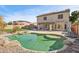 Backyard showing a large pool with rock features, grassy area, patio, and the house's rear exterior at 15934 W Banff Ln, Surprise, AZ 85379