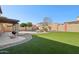 Backyard featuring a pool with rock waterfall, synthetic grass, a covered patio and a grill for outdoor entertaining at 15934 W Banff Ln, Surprise, AZ 85379