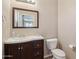 Cozy bathroom with sink, wood cabinet, toilet, large mirror and sink provides functionality in a small space at 15934 W Banff Ln, Surprise, AZ 85379