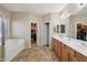 Bathroom with dual sinks, a soaking tub, tile floors and a large walk-in closet at 15934 W Banff Ln, Surprise, AZ 85379