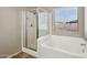 Bright bathroom featuring a shower, bathtub, and window with views of the neighborhood at 15934 W Banff Ln, Surprise, AZ 85379