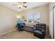 Bedroom with a ceiling fan, large window, desk, computer, and comfy chair at 15934 W Banff Ln, Surprise, AZ 85379