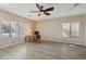 Bright living room filled with light from several windows, featuring wood-look floors and ceiling fan at 15934 W Banff Ln, Surprise, AZ 85379