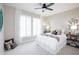 Cozy bedroom with a tufted headboard, soft carpeting, white curtains, ceiling fan, and a serene ambiance at 16464 W Una Noche Ct, Surprise, AZ 85374