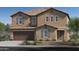 Charming two-story home featuring a tan stucco exterior, shuttered windows, attached two-car garage and desert landscaping at 17166 W Oberlin Way, Surprise, AZ 85387