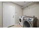 Functional laundry room with washer and dryer, shelving for storage, and tile flooring for easy maintenance at 1723 E Behrend Dr, Phoenix, AZ 85024