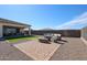 Backyard patio area with outdoor seating, artificial turf, and a covered patio with barbecue at 17878 W Amber Ridge Way, Goodyear, AZ 85338