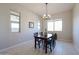 Dining area with a wood table, six chairs, modern light fixture, and multiple windows at 17878 W Amber Ridge Way, Goodyear, AZ 85338