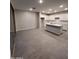 An open-concept living space with neutral walls, wood-style tile and a kitchen with white cabinetry at 18243 W Larkspur Dr, Goodyear, AZ 85338