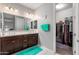 Bright bathroom with dual sinks, dark wood cabinets, white countertops, large mirror, and doorway to walk-in closet at 19806 W San Miguel Ave, Litchfield Park, AZ 85340