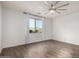 Bright bedroom features wood-look tile flooring, neutral paint, a ceiling fan, and a window with backyard views at 19982 W Glenrosa Ave, Litchfield Park, AZ 85340