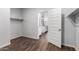 Walk-in closet features wood-look tile flooring and a doorway into a bathroom with white cabinets at 19982 W Glenrosa Ave, Litchfield Park, AZ 85340