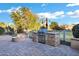 An outdoor kitchen on a paver patio featuring a built-in grill and a charming stone fire pit with comfortable seating at 20391 N Sunrise Ln, Maricopa, AZ 85138