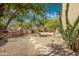 Lush backyard featuring desert landscaping, mature trees, and a stone pathway at 2070 W Bromm Ln, Wickenburg, AZ 85390