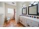 Bright bathroom featuring dual sinks, white cabinetry, and beautiful terracotta tile flooring at 2070 W Bromm Ln, Wickenburg, AZ 85390