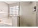 Bright bathroom showcasing a tub, walk-in shower with glass door, and decorative glass block window at 2190 W San Tan Hills Dr, San Tan Valley, AZ 85144