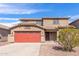 Two-story home featuring a red two-car garage, desert landscaping, a tile roof, and a covered front porch at 2190 W San Tan Hills Dr, San Tan Valley, AZ 85144