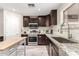 Well-lit kitchen with stainless steel appliances, granite countertops, tile backsplash, dark cabinets, and an island at 2190 W San Tan Hills Dr, San Tan Valley, AZ 85144