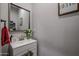 Modern half bathroom featuring a sink, mirror, and flowers on a gray painted wall with a red towel at 2246 E Sheridan St, Phoenix, AZ 85006