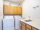 Laundry room with a sink, front loading washer and dryer, and wood upper cabinets at 27141 E Javelina Dr, Florence, AZ 85132