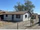 A charming single-story home features a white exterior, chain-link fence and mature trees against a clear blue sky at 2837 W Almeria Rd, Phoenix, AZ 85009