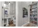 Stylish powder room with pedestal sink, decorative mirror, and adjacent built-in shelving at 28714 N Verde River Way, Rio Verde, AZ 85263