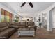 A living room featuring a large sectional sofa, wood flooring, and an open view into the adjacent kitchen at 4245 S 247Th Dr, Buckeye, AZ 85326