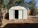 Exterior view of home's backyard shed with open doors on a dirt lot with trees above and fence line in the background at 5000 W Osborn Rd, Phoenix, AZ 85031